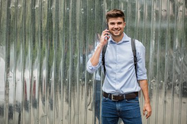 Kurumsal adam. sırt çantası Gri Metalik arka plan üzerinde kendinden emin ve mutlu olan akıllı casual adam