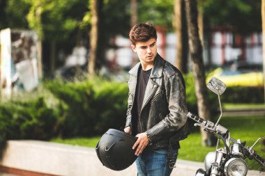 Genç ve güzel. Bisiklete binmeyi bekleyen yakışıklı adam yanındaki bir şehir merkezinde onun motosiklet