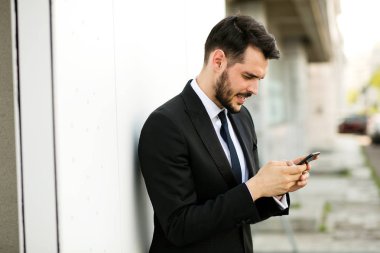 cep telefonunu kullanarak ve gülümseyen, reciving iyi haberler takım elbiseli şık yakışıklı