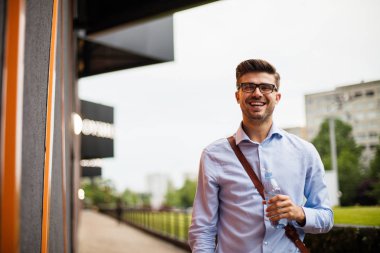 hidrasyon zihin. yakışıklı zeki casual adam gözlük ve soğuk bir şişe su içme dışında deri çanta