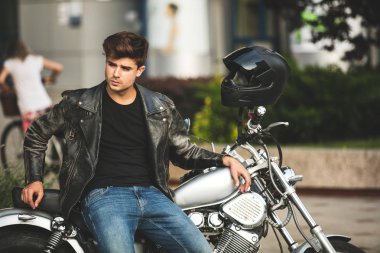 Genç ve güzel. yakışıklı ve rahatlatıcı bir adam motorsikletiyle içinbeklediğini şehir merkezinde oturan