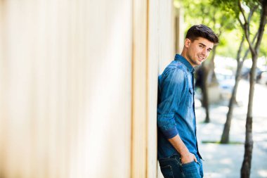 cofident genç adam onun girlsfriend için sokakta bekleyen bir ahşap duvar karşı ayakta