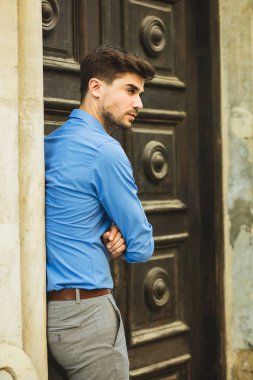 Konuklar veya istemciler için bekliyor. zarif adam sabırla bekleyen biri için eski bir ahşap kapı önünde ayakta