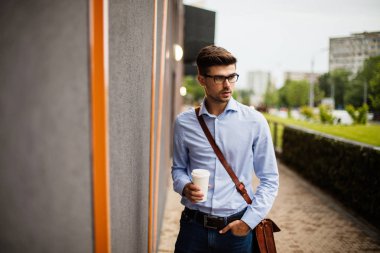 kahve .handsome akıllı bir casual adam gözlük ve deri çanta dışında bir kağıt bardak kahve ile office giden yolda götürün