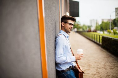 kahve .handsome akıllı bir casual adam gözlük ve deri çanta dışında bir kağıt bardak kahve ile office giden yolda götürün
