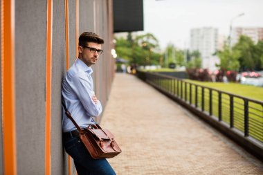 zor bir gün. yakışıklı akıllı casual adam gözlük ve mavi gömlek, dışında yorgun ve üzgün gri bir duvara dinlenme