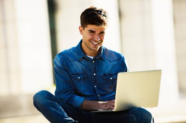 ön kamera, büyük bir binanın önünde isteyen dizüstü bilgisayar ile gülümseyen adam