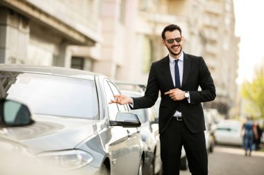 başarılı adam ile büyük gösteren gülümseme onun yeni araba, zarif işadamı dışında onun araç yanındaki