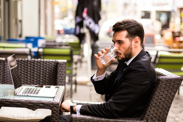 Portrait of handsome successful man drink coffee and look to the digital tablet screen sitting in coffee shop, business man drinking water in a break and trying to relax