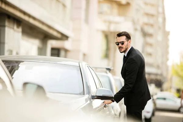 Zelfverzekerde Elegante Man Pak Met Zonnebril Steping Zijn Luxeauto Straat — Stockfoto