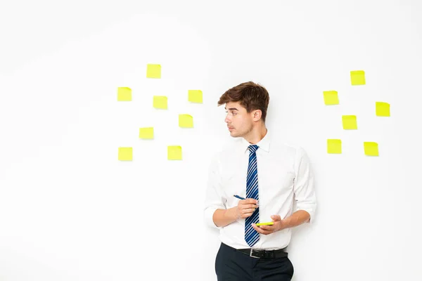 office guy at work, writing on post it on white wall, reminder notes, plans and  objectives