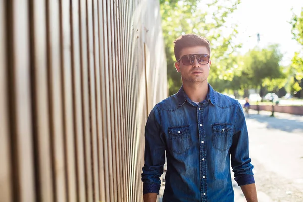 street fashion. fashionable man in jeans outfit, outdoor on the street with sunglases