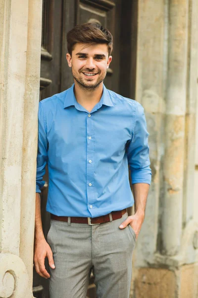 waiting for the guests or clients. smiling elegant man waiting for someone and smiling to camera outside in front of his door