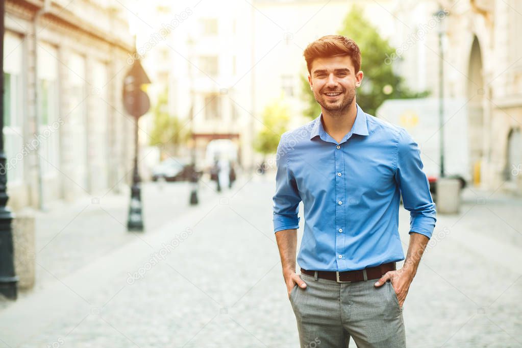 young handsome and confident guy in smart casual outfit, office day, standing outside on the street and looking to camera