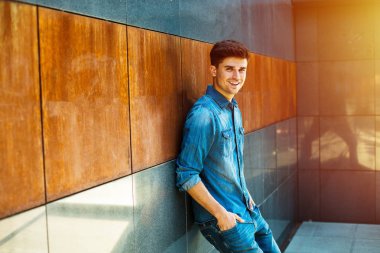 Eller cepler ve kamera, Bütün Jeans isteyen ile gülümseyen adam bir minimalist oda ayakta karşı yaslanmış rahat