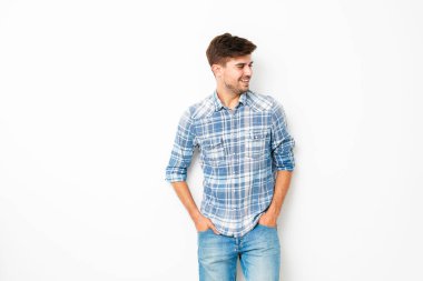tatlı çocuk, kot pantolon ve kareli gömlek boş uzayda ile beyaz duvarda duran genç adam