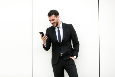 cep telefonunu kullanarak ve gülümseyen, reciving iyi haberler takım elbiseli şık yakışıklı