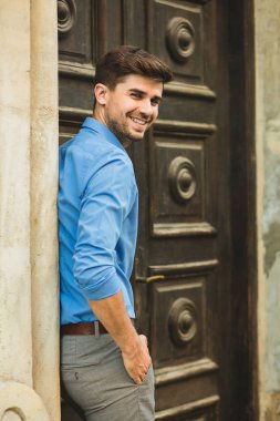 Konuklar veya istemciler için bekliyor. birini bekliyor ve onun kapısının önünde dışında kameraya gülümseyen gülümseyen zarif adam