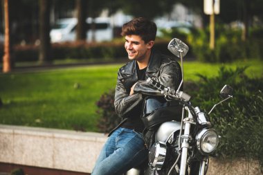 Genç ve güzel. yakışıklı ve rahatlatıcı bir adam motorsikletiyle içinbeklediğini şehir merkezinde oturan