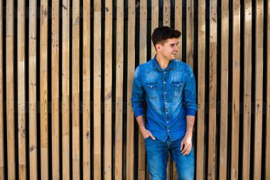 serin ve modern. yakışıklı seksi adam onu, neşeli ve yan için arıyorum ayakta yanındaki metni için boş alan ile ahşap arka plan üzerinde kot kıyafeti
