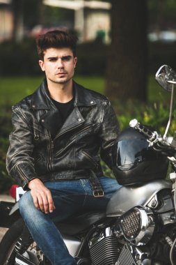 Genç ve güzel. kameraya bakarak birini bekliyor ve bir yere bir şehir merkezinde rahatlatıcı onun motosiklet üzerinde oturan yakışıklı adam