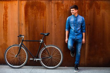 şehrin hızlı. kot kıyafeti yanında onun tek hız bisiklet paslı bir arka plan üzerinde şık bir adamla bir şehirde güzel bir ulaşım kavramı