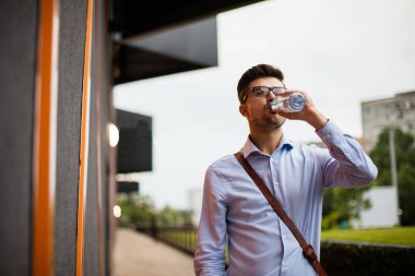 hidrasyon zihin. yakışıklı zeki casual adam gözlük ve soğuk bir şişe su içme dışında deri çanta