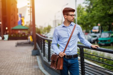 office sonra eve gidiyorum. yakışıklı zeki casual adam gözlük ve deri çanta dışında işten sonra yürüyüş