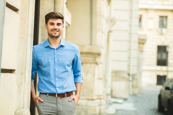 young man in elegant outfit, smart casual, office day, in a break of work outside, smiling to camera with confidence