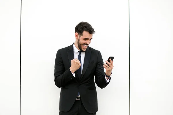 英俊优雅的男子在西装使用他的手机和微笑 Reciving 好消息 — 图库照片