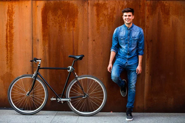 şehrin hızlı. kot kıyafeti yanında onun tek hız bisiklet paslı bir arka plan üzerinde şık bir adamla bir şehirde güzel bir ulaşım kavramı