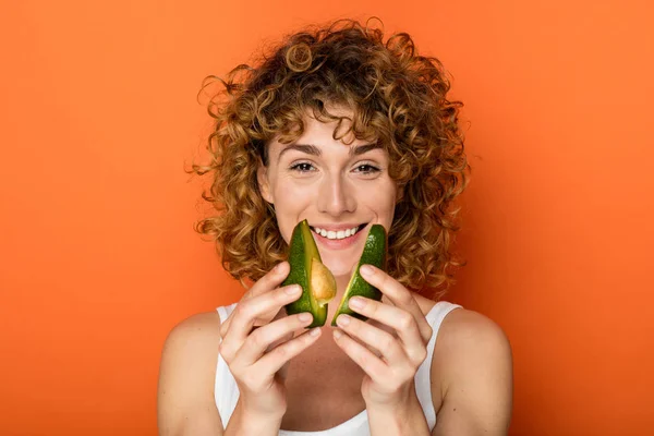 Junge Lockige Frau Mit Einer Avocado Der Hand Auf Orangefarbenem — Stockfoto