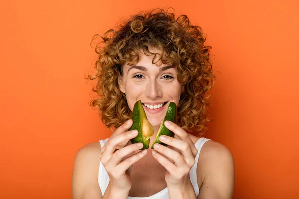 Unga Lockigt Kvinna Som Håller Avokado Händerna Orange Bakgrund — Stockfoto