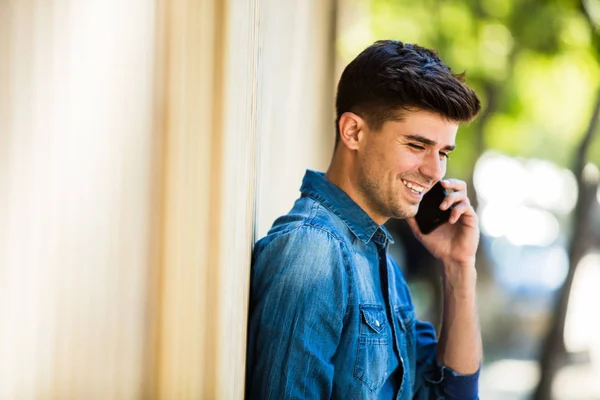 Mladý Muž Džínách Oblečení Mluvit Mobilním Telefonu Usmívá Venku Ulici — Stock fotografie