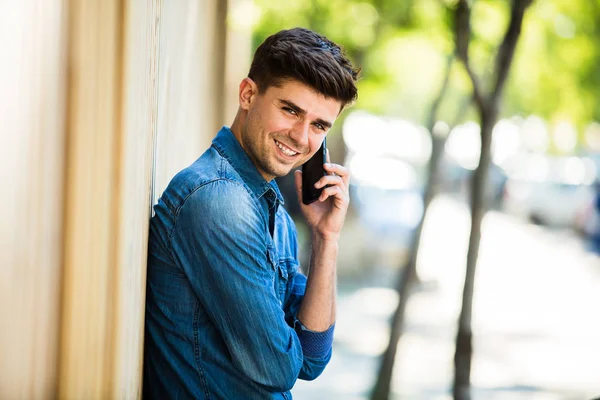 Mladý Muž Džínách Oblečení Mluvit Mobilním Telefonu Usmívá Venku Ulici — Stock fotografie