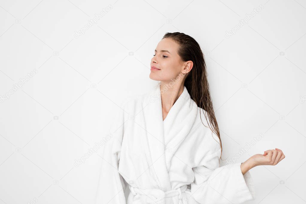 young natural and beauty woman standing with wet hair after a shower or a hair treatment in bathrobe on white background