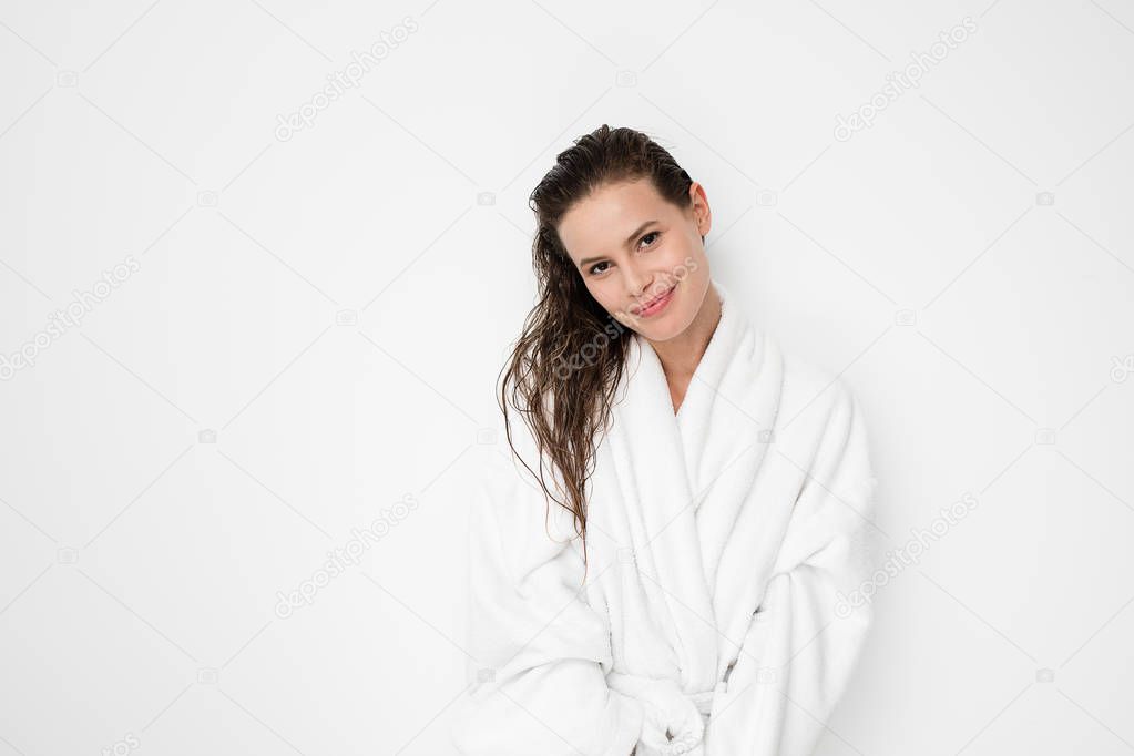 young natural and beauty woman standing with wet hair after a shower or a hair treatment in bathrobe on white background