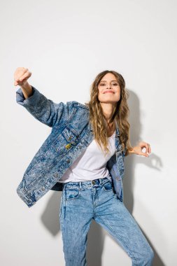 Beyaz arka plan üzerinde kot kıyafetiyle kamera için poz genç gülümseyen kadın