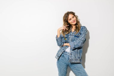 Beyaz arka plan üzerinde duran ve tarafına seyir kot kıyafeti gülümseyen genç kadın