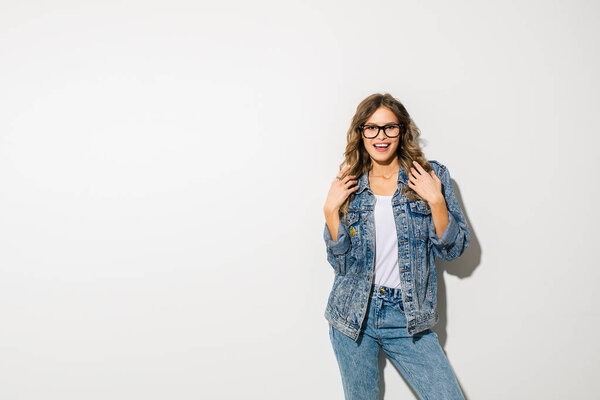 trendy beautiful woman in  jeans with eyeglasses posing on white background