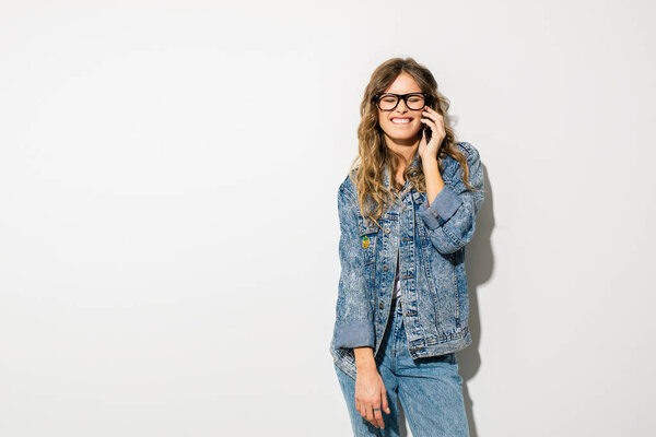 young woman standing on white background and having a conversation on cellphone