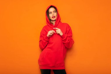 poz ya da bir şey bekliyor serin genç hipster sarı zemin üzerine kırmızı kukuletalı baş başlık ile