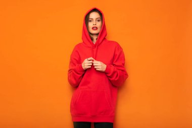 poz ya da bir şey bekliyor serin genç hipster sarı zemin üzerine kırmızı kukuletalı baş başlık ile