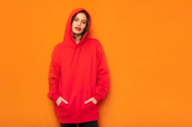 poz ya da bir şey bekliyor serin genç hipster sarı zemin üzerine kırmızı kukuletalı baş başlık ile