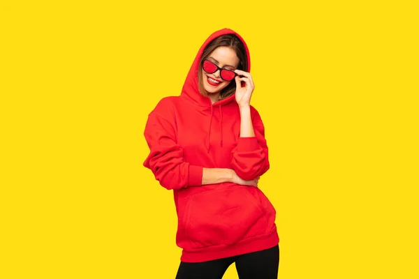 黄色の背景に赤のパーカー若いと肯定的な女性 — ストック写真