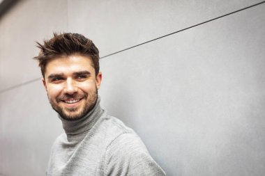 gülümseyen çekici adam gri modern duvar