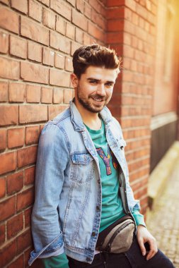 bir tuğla duvara poz ve kamera, osteopenik resim ile modern bir öğrenci için gülümseyen yakışıklı ve güzel genç adam