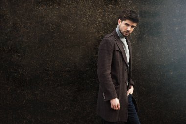 çekici bir adam duvara yaslanmış bir ceket stand giyinmiş