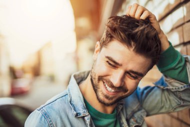 serin bir tutum ile bir duvar yanında poz serin ve seksi genç adam portresi