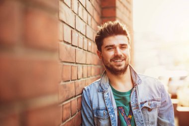 bir tuğla duvara poz ve kamera, osteopenik resim ile modern bir öğrenci için gülümseyen yakışıklı ve güzel genç adam